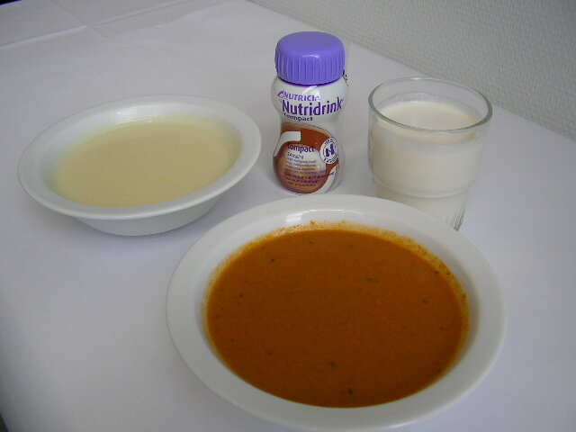 Billedet viser en skål suppe, koldskål og et glas mælk.