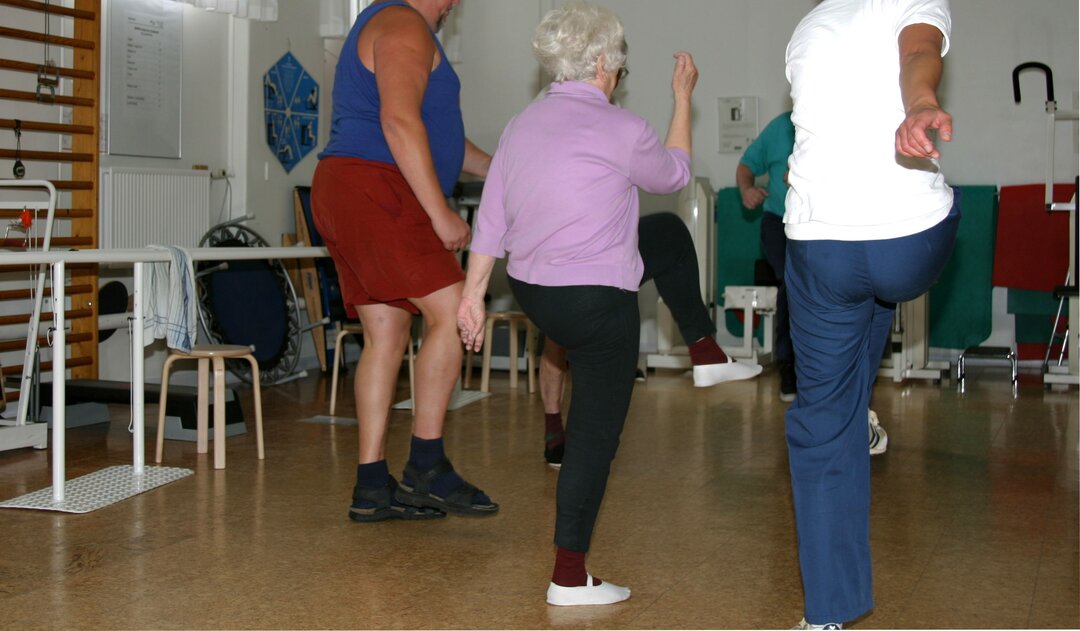 Billedet viser patienter, i et hold, træne med løft af arm og ben