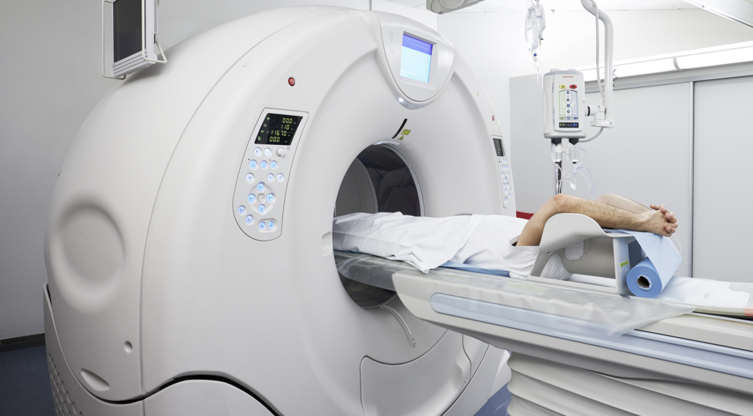 Patient liggende på ryggen i CT-skanner.