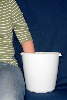 Billedet viser en hånd i en spand med vand i.