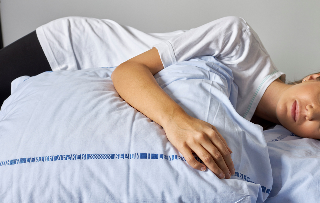 Foto af en patient, der ligger på siden og hviler sin arm på en pude.