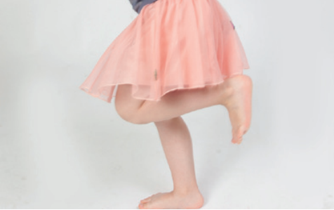 Et billede af et barn i tylskørt, der står på et ben. 
