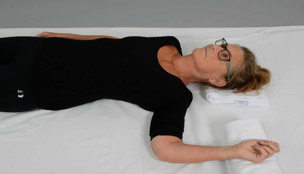 Billede af en kvinde, der ligger i sengen med en pude under underarmen.