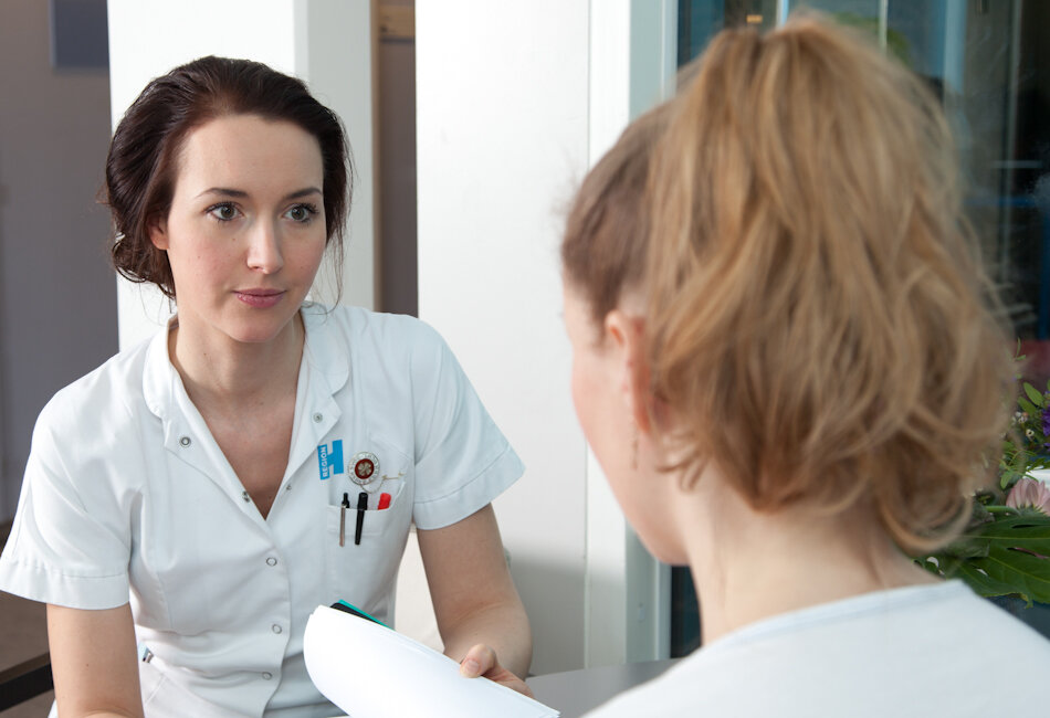 Billedet viser en sygeplejerske tale med en patient.