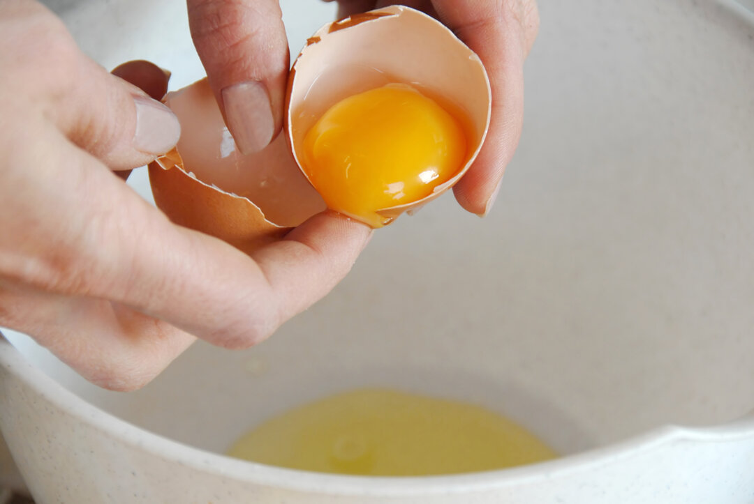 Billedet viser en æggeblomme blive delt fra æggehviden.