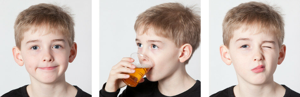 Billedet viser en dreng smile, drikke juice og lukke ét øje.