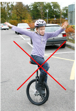 Billedet viser et barn cykle på en ethjulet cykel.