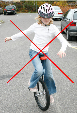 Pige på ethjulet cykel med rødt kryds over