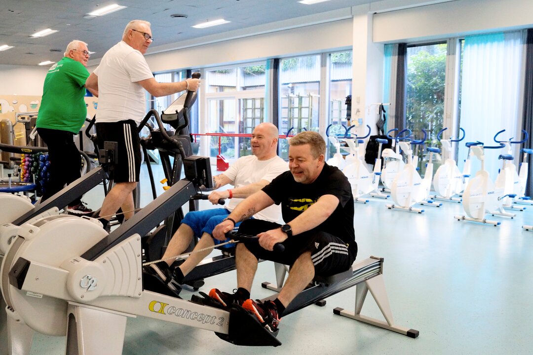 Billedet viser fire træne i et fitnessrum.