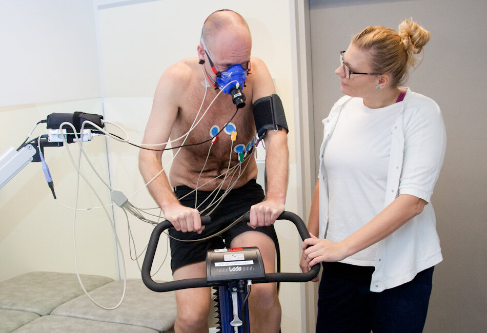 Billedet viser en patient på en cykel med iltmaske og elektroder på.