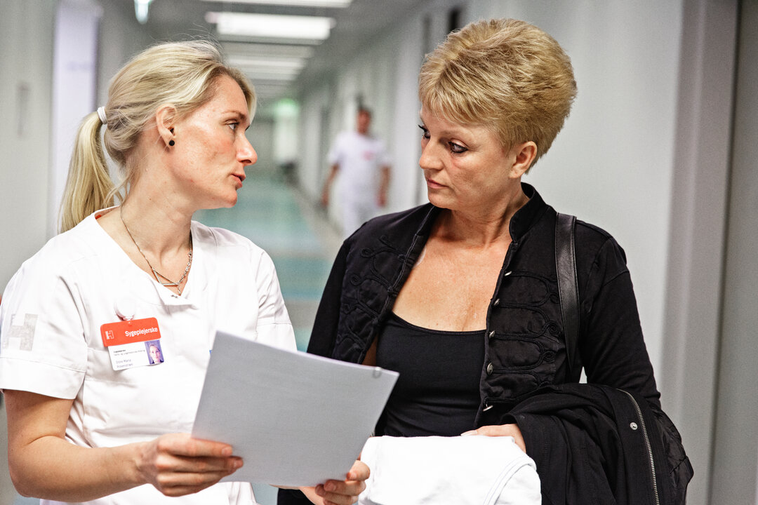 Billedet viser en sygeplejerske, der hjælper en patient. 
