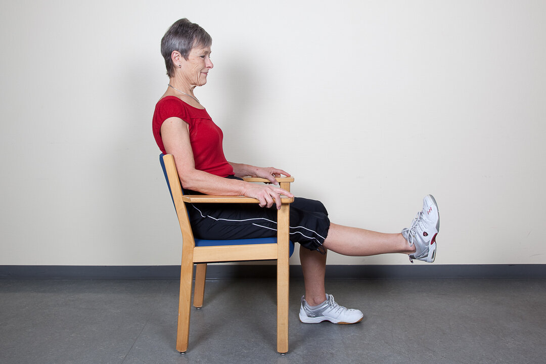 Øvelsen øger styrken i lårene og bevægeligheden i knæene.  Sid tilbage på stolen.  • Stræk knæet på det opererede ben helt ud. • Hold stillingen, tæl langsomt til 10 og sænk langsomt ned igen.