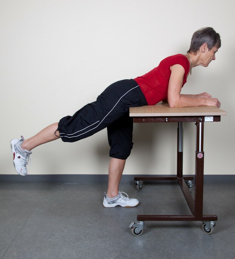 4. Øvelse for hoftens bagside  Lig ind over et bord med støtte på underarmene, træk maven lidt ind.  Før det opererede ben bagud og op, og sænk det igen.  Hold knæet strakt under hele bevægelsen.   Udfør øvelsen med både højre og venstre ben.