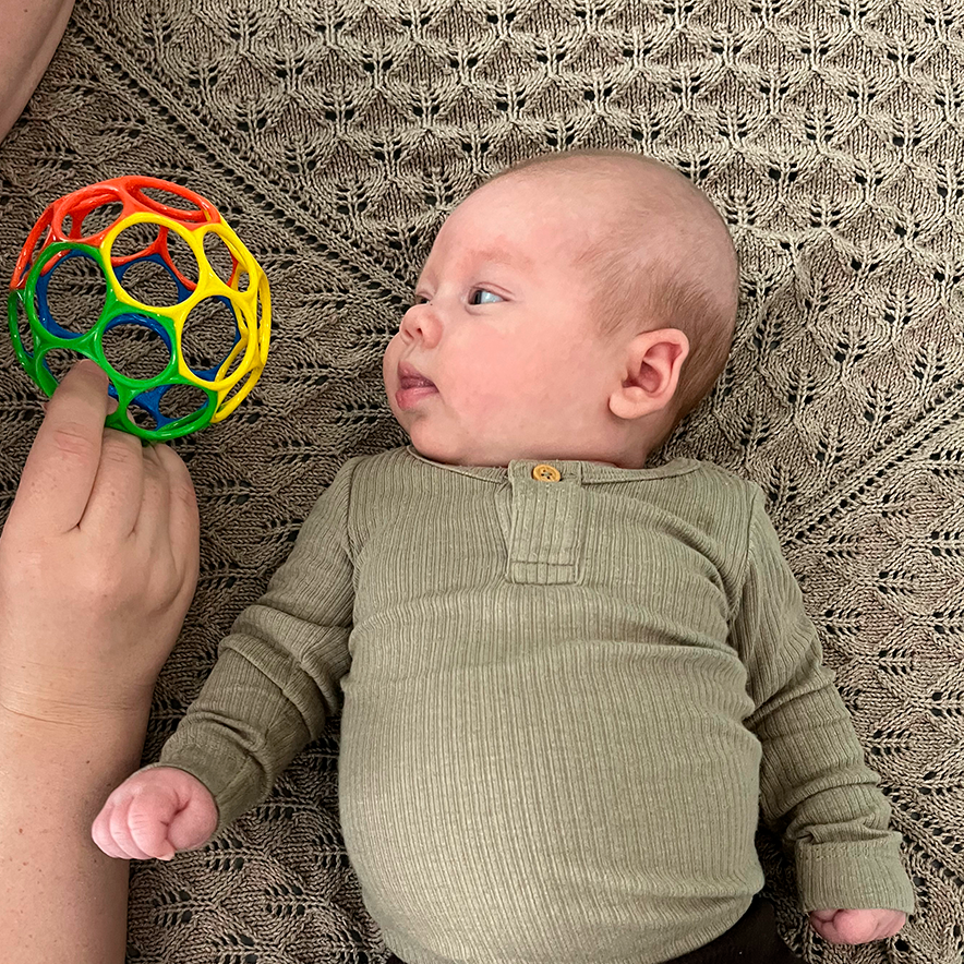 Billede af en person, der leger med en baby, der ligger på ryggen.
