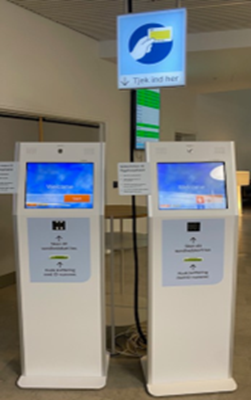 Billede af standerne i forhallen, hvor du skal tjekke ind med sundhedskort. sundhedskort