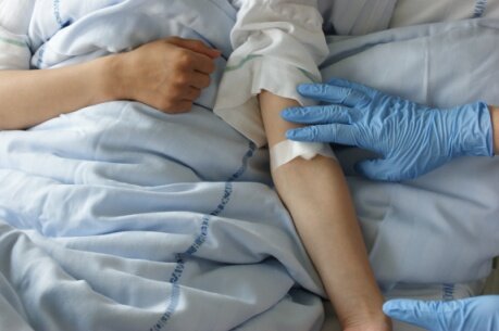 Sygeplejerske sætter plaster på patientens arm