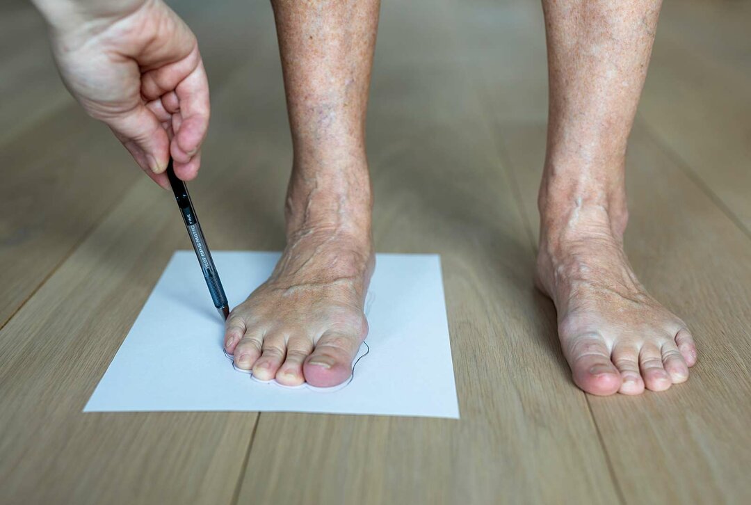 En person tegner omridset af en andens fod.